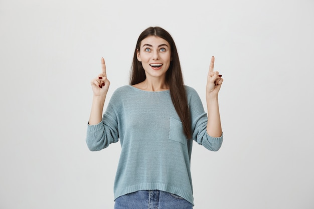 Excité heureux, femme souriante pointant et levant