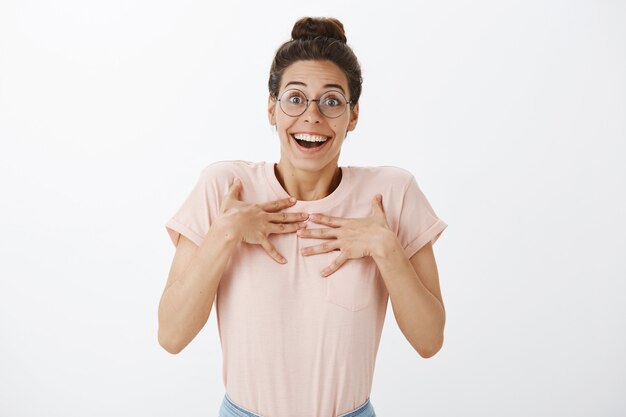 Excité heureux jeune femme élégante posant contre le mur blanc