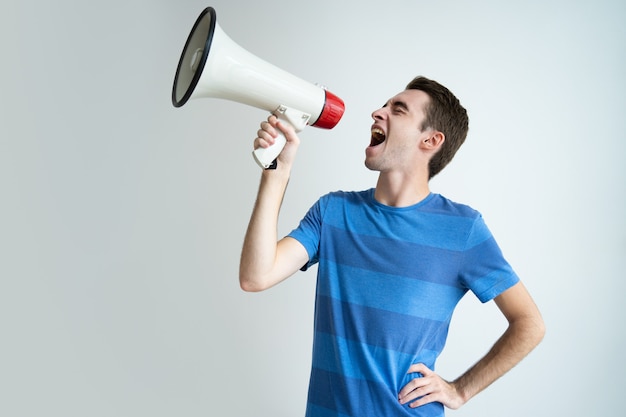 Excité homme attrayant criant dans le mégaphone