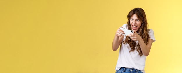 Excité intense gamer ludique fille geek jouant à un jeu de smartphone génial tenir le téléphone mobile à l'horizontale