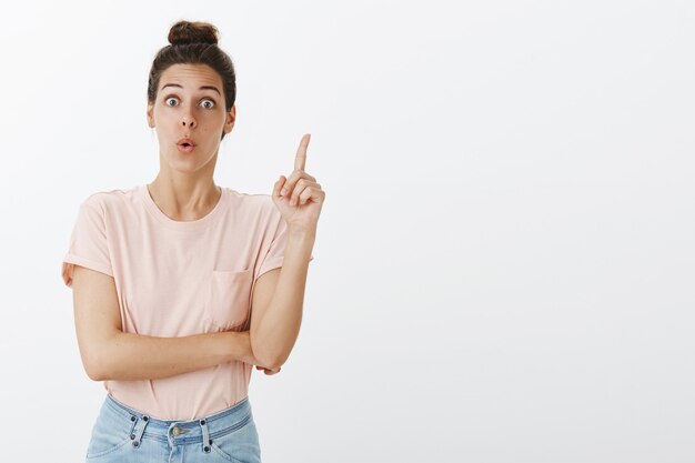 Excité jeune femme élégante posant contre le mur blanc