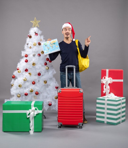 excité, jeune homme, à, sac à dos jaune, tenue, carte, sur, gris