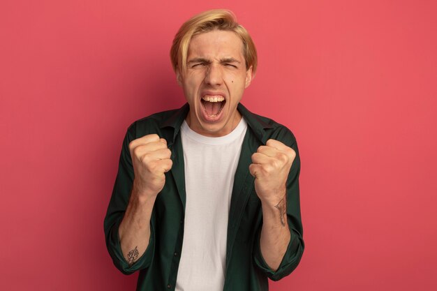 Excité jeune mec blond vêtu d'un t-shirt vert vous montrant le geste