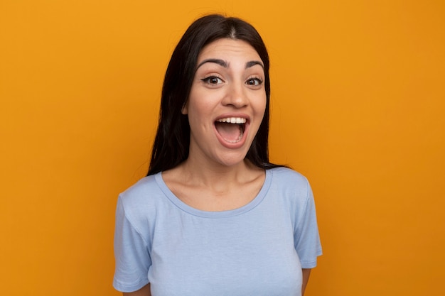 Excité jolie femme brune regarde avant isolé sur mur orange