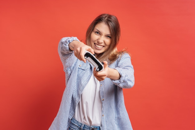 Excité occasionnel jeune femme jouant à des jeux vidéo s'amuser sur rouge