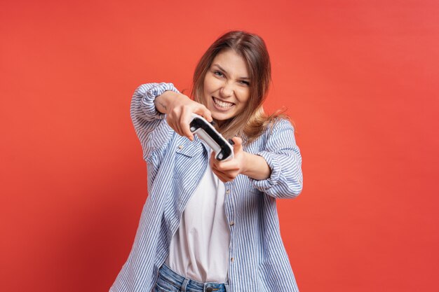 Excité occasionnel jeune femme jouant à des jeux vidéo s'amuser sur rouge