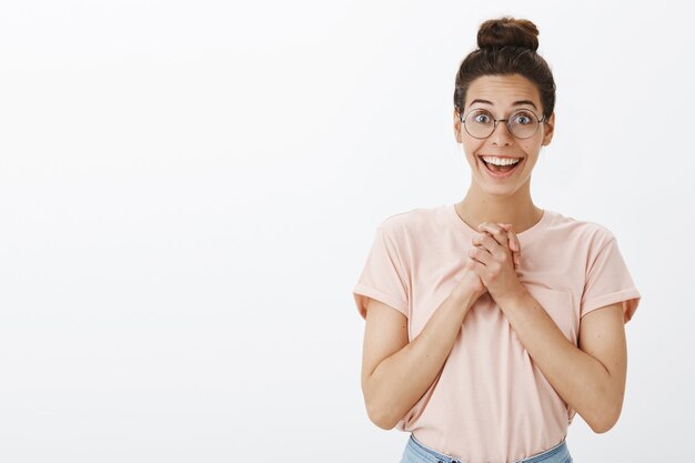 Excité souriant jeune femme élégante posant contre le mur blanc