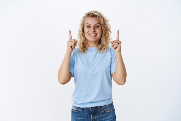 Excitée et heureuse amie charismatique montrant une vente ou un produit impressionnant levant les doigts et souriant ravie ne peut pas attendre que son petit ami l'achète pour le nouvel an sur fond gris