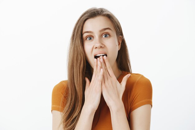 Excitée et surprise, une belle fille fascinée réagit à une scène impressionnante, haletante étonnée