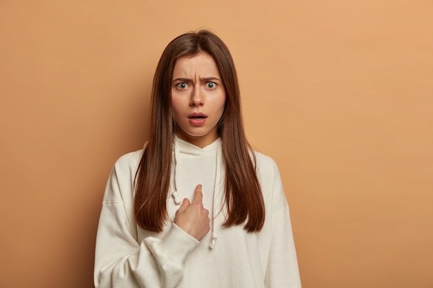 Excusez-moi. Une femme indignée et perplexe se pointe du doigt, fronce les sourcils avec mécontentement, étant confuse de faire quelque chose de mal, pose des questions