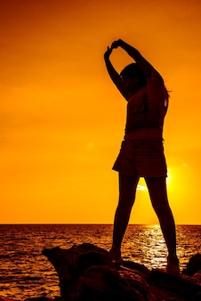 Exercice de femme silhouette sur le coucher du soleil de la plage. sport et mode de vie sain.