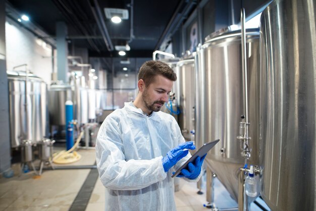 Expert technologue à l'aide d'un ordinateur tablette dans la ligne de production d'usine alimentaire