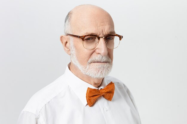 Expression faciale humaine, attitude et perception de la vie. Portrait d'un homme d'âge mûr à tête chauve âgé sérieux bouleversé avec des rides sur son front et barbe grise serrant les yeux, ayant un regard suspect