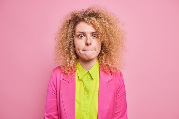 Expressions du visage humain. Une jeune femme aux cheveux bouclés avec une expression surprise appuie sur les lèvres se sent inquiète