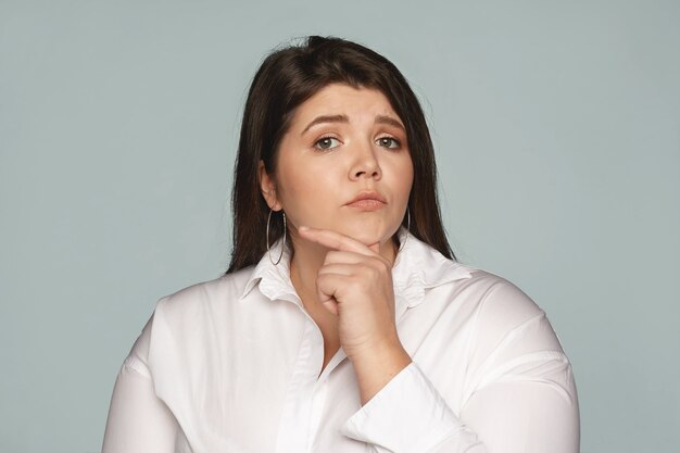 Expressions faciales humaines, sentiments et émotions. Pensive jeune femme d'affaires européenne réfléchie avec un grand corps sinueux touchant son menton