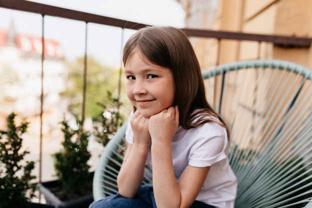 À l'extérieur gros plan portrait de jolie petite fille mignonne assise sur le balcon