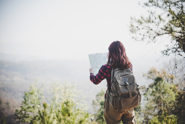 Photo gratuit face arrière de la fille voyageur qui recherche la bonne direction sur la carte, en voyageant en randonnée dans la montagne. concept de voyage.