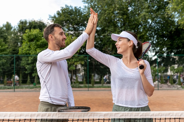 Face couple heureux sur le court de tennis