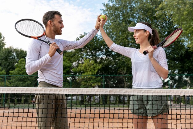 Face couple heureux sur le court de tennis