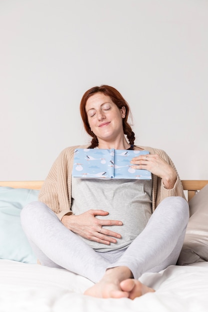 Faible angle enceinte femme lisant des livres pour bébés