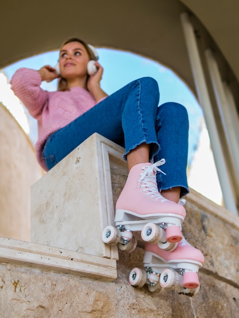 Faible angle de femme écoutant de la musique en patins à roulettes