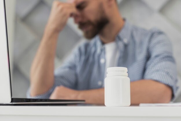 Faible angle, jeune homme, au bureau, avoir, mal tête