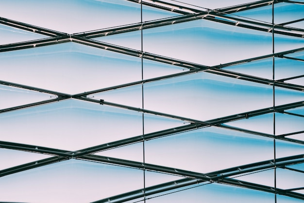 Photo gratuite faible angle de vue de câbles métalliques géométriques sur un bâtiment en verre