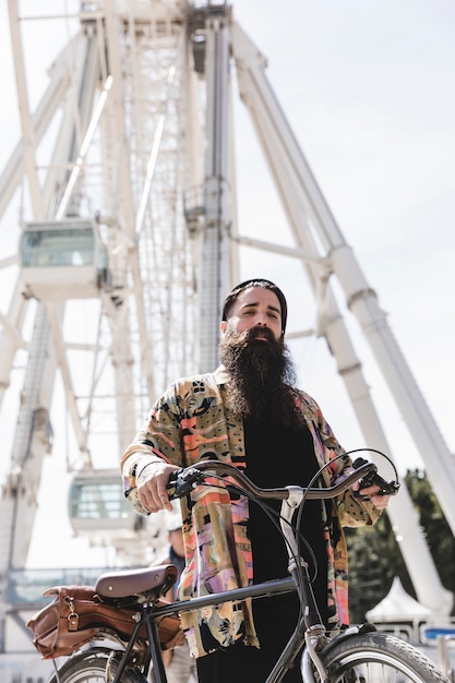 Photo gratuite faible angle de vue d'un cycliste debout près de la grande roue