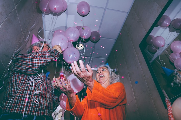 Photo gratuite faible angle de vue du couple heureux senior jetant les confettis à la fête