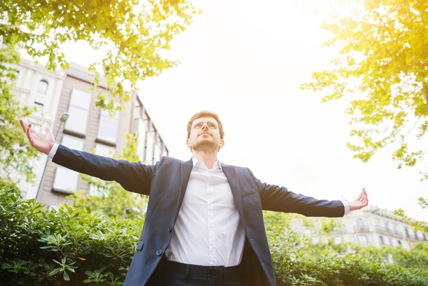 Faible angle, vue, homme affaires, debout, devant, bâtiment, tendre bras