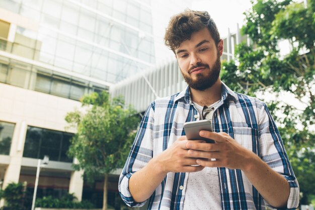 Faible angle de vue d'un homme lisant le message d'un ami à l'extérieur