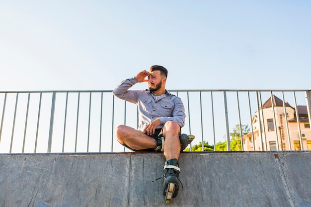 Faible angle de vue d&#39;un jeune patineur mâle protégeant ses yeux