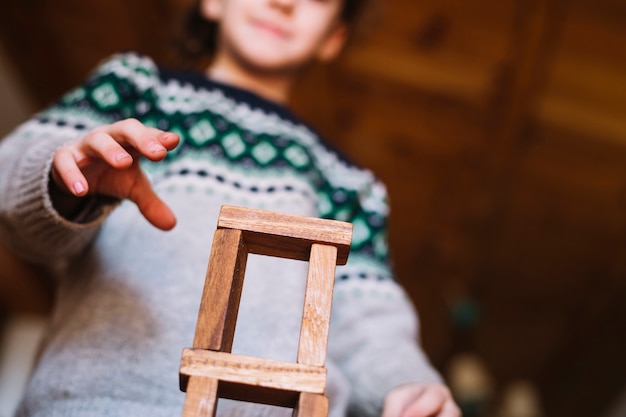 Faible angle de vue de la main de la jeune fille jouant avec des blocs de bois empilés