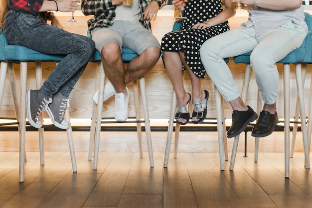 Faible section d&#39;amis assis sur un tabouret de bar