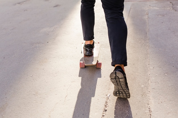 Photo gratuite faible section vue des pieds d'une personne patinage sur planche à roulettes en bois