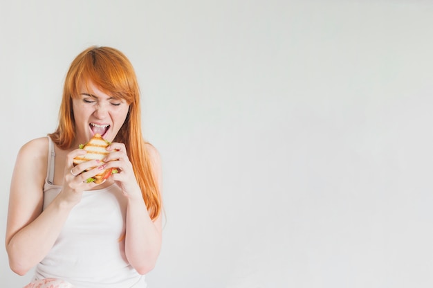 Faim jeune femme manger un sandwich grillé sur fond blanc