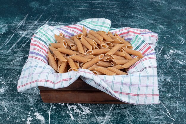 Faire brunir les pâtes penne crues dans un panier en bois. Photo de haute qualité