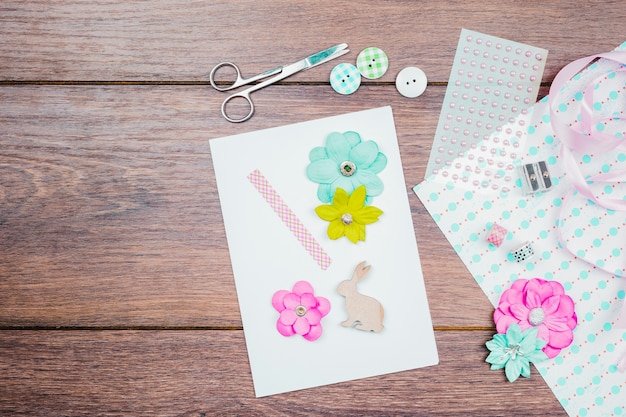 Photo gratuite faire une carte de voeux avec une fleur; boutons; ruban et perles sur table en bois