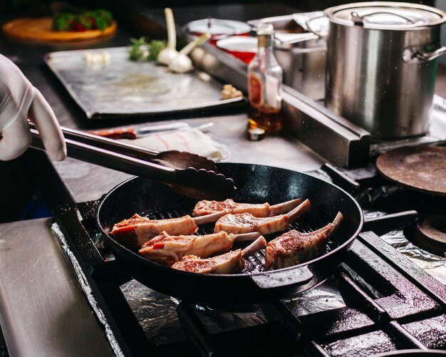 Faire cuire les côtes de viande à l'intérieur d'une poêle en métal ronde dans la cuisine