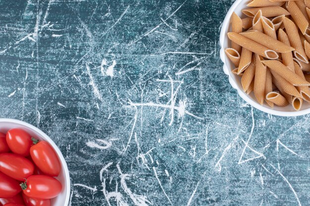 Faire dorer les penne et les tomates dans des bols blancs. Photo de haute qualité