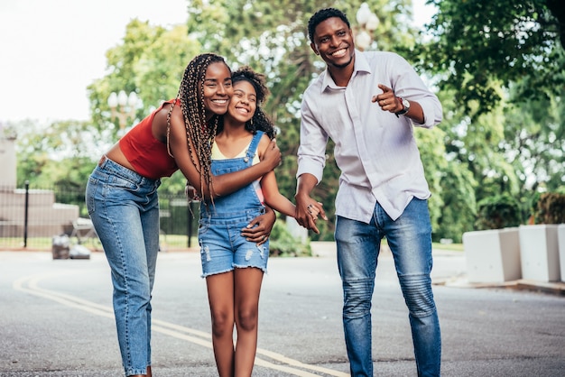 Famille afro-américaine profitant d'une journée ensemble en marchant à l'extérieur dans la rue. Notion urbaine.