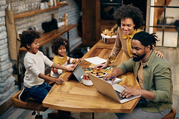 Famille afro-américaine utilisant la technologie sans fil à la maison