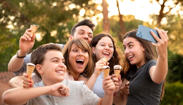 Famille appréciant la crème glacée ensemble à l'extérieur et prenant le selfie