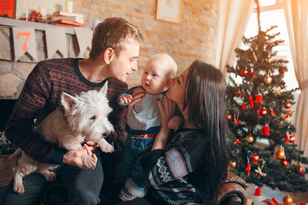 Famille assis sur un canapé avec un chien à Noël