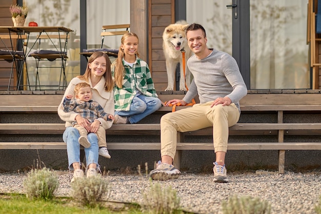 Famille Assise Sur Les Marches Regardant La Caméra Et Le Chien