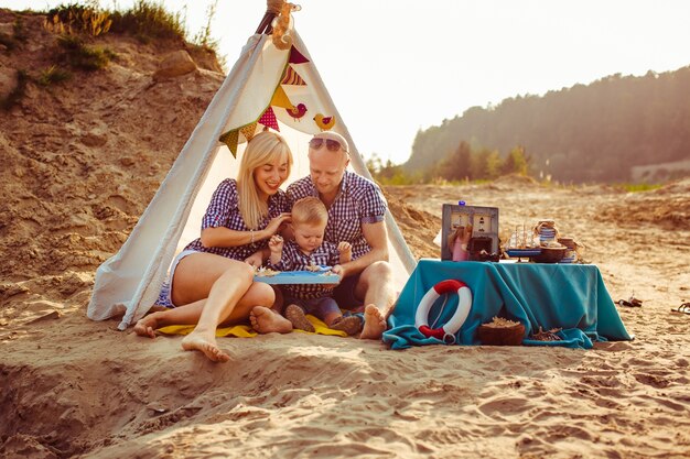 &quot;Famille assise sur sable sous tente&quot;