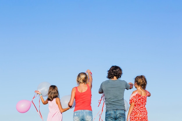 Photo gratuite famille avec des ballons sur fond de ciel