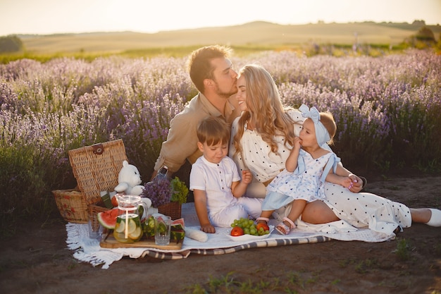 Famille sur champ de lavande. Les gens en pique-nique. Mère avec enfants mange des fruits.