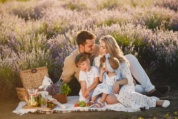 Famille sur champ de lavande. Les gens en pique-nique. Mère avec enfants mange des fruits.