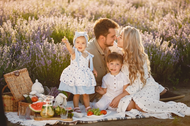 Famille sur champ de lavande. Les gens en pique-nique. Mère avec enfants mange des fruits.